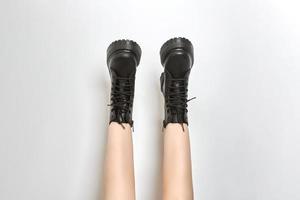 Woman legs in black combat boots on high heel platform with lug soles upside down, white background photo