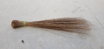 closeup view of a single Broom from rods Isolated on grey cement background photo