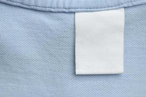 etiqueta de ropa blanca en blanco para el cuidado de la ropa sobre fondo de tela de camisa azul foto