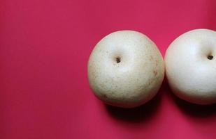 Two pyrus fruits isolated on red background, top view and negative space. photo