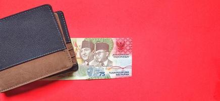 la última edición de billetes de rupias indonesias por valor de 75.000 rupias aisladas en un fondo rojo. foto