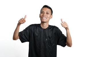hombre asiático con camiseta negra de entrenamiento, sintiéndose feliz y dando pulgares hacia arriba. aislado por fondo blanco foto