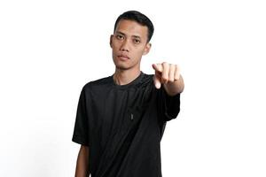 Asian man wearing black training shirt, pointing at you. Isolated by white background photo