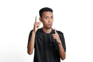 excited asian man wearing black training t-shirt, pointing to copy space. Isolated by white background photo