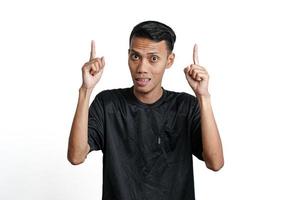 excited asian man wearing black training t-shirt, pointing to copy space. Isolated by white background photo