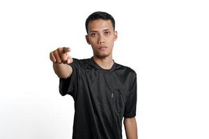 Asian man wearing black training shirt, pointing at you. Isolated by white background photo