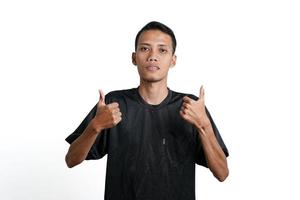 hombre asiático con camiseta negra de entrenamiento, sintiéndose feliz y dando pulgares hacia arriba. aislado por fondo blanco foto