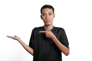 excited asian man wearing black training t-shirt, pointing to copy space. Isolated by white background photo