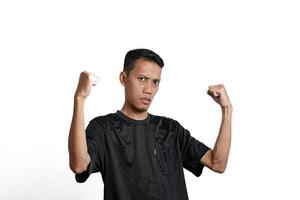 asian man wearing black training t-shirt, showing a strong stance with raised arms and muscles. Isolated by white background photo