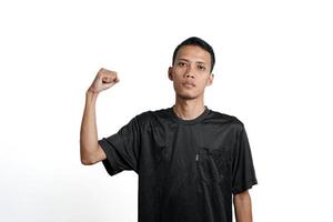 asian man wearing black training t-shirt, showing a strong stance with raised arms and muscles. Isolated by white background photo