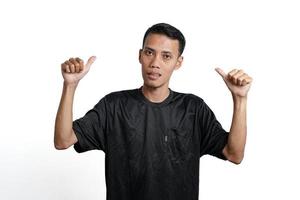 asian man wearing black training t-shirt, feeling happy and giving thumbs up. Isolated by white background photo