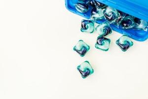 Blue-and-blue washing capsules are scattered on a white background. The process of washing clothes. Liquid washing gel. photo