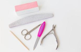 Professional manicure set on a white table. The concept of hand care, salon procedures. File, scissors, buff, bamboo stick, cuticle nippers. photo