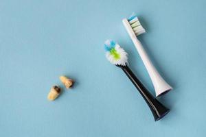 A modern electric toothbrush on a blue background next to extracted wisdom teeth affected by caries. Tooth extraction operation. Hygiene concept for daily care. Old and new toothbrush. photo