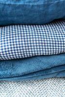 ropa de cama de diferentes tonos de azul, azul, blanco y diferentes estructuras se apilan una encima de la otra, el concepto de hogar y comodidad. foto