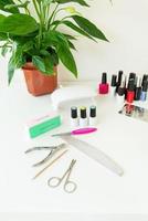 el concepto del espacio de trabajo del maestro del salón de uñas. vista superior de las herramientas de manicura en una mesa blanca. procedimientos cosméticos y cuidado de manos. foto