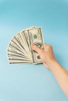 Female hands holding 100 dollar bills isolated on blue background.