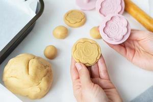 The process of making cookies with shapes in the form of flowers, a rolling pin and a tray, the concept of cooking, baking at home. photo