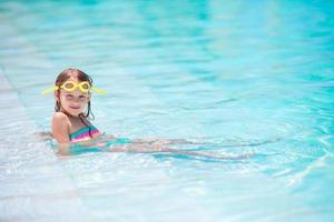 Little happy adorable girl in outdoor swimming pool photo