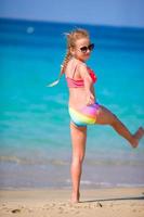 Adorable active little girl at beach during summer vacation photo