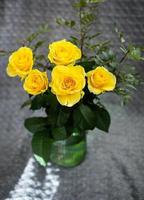 Beautiful yellow roses in a green vase stand on a blanket. Surprise and holiday concept. photo