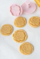 The process of making cookies with forms in the form of flowers, a rolling pin and a baking sheet - ready-made cookies with an imprint from the form. The concept of baking at home. photo