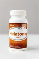 Kyiv, Ukraine - 27 January 2022 Jar of Melatonin capsules from GNC. 3 mg tablet to improve sleep and fight insomnia - nutritional supplement and medicine for men and women. Shallow depth of field. photo