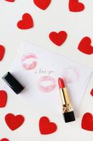 la inscripción te amo en un sobre blanco con una huella de labios con lápiz labial rojo sobre un fondo de pequeños corazones rojos. el concepto de st. Día de San Valentín. foto