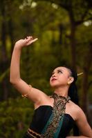 Balinese women raise their hands in the air while dancing in green costumes while performing in the festival photo