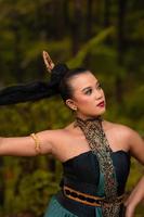 Gorgeous Asian woman in makeup with black hair and red lipstick wearing golden jewelry during the dance performance photo