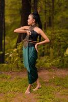 Beautiful Indonesian dancers with traditional green costumes and black tied hair posing inside the forest photo