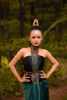 Balinese woman in makeup and gold jewelry on her body with a black costume standing photo