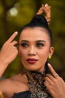 Beautiful Asian woman with makeup and tied black hair wearing a piece of black jewelry before performing dancing on the stage photo