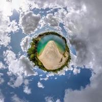 green tiny planet in blue sky with beautiful clouds. Transformation of spherical panorama 360 degrees. Spherical abstract aerial view. Curvature of space. photo