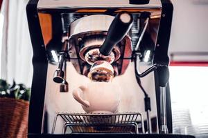 Coffee extraction from the coffee machine with a portafilter pouring coffee into a cup,Espresso poruing from coffee machine at coffee shop photo