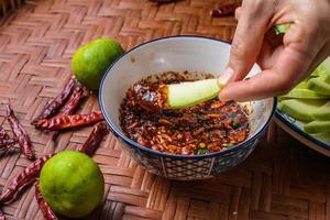 manos sumergiendo mangos en salsa de pescado dulce. mango verde con salsa de pescado dulce una comida favorita en tailandia.
