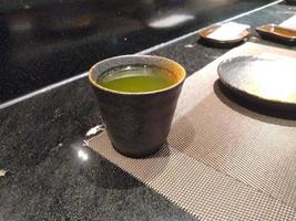 cup of  green tea in Japanese restaurant table with dishs photo