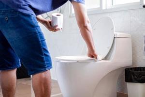 Man holding tissue paper and wipe cleaned the flush toilet of the public toilet before using it for protection against germs, The concept of hygiene in daily life. photo