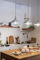 Vertical shot of a kitchen with hanging chandeliers and a table with cakes and pastries photo