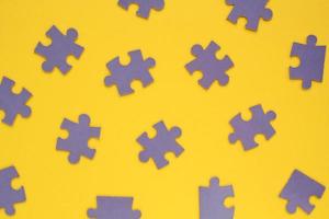 Violet mosaic game details of jigsaw puzzle elements on yellow background. Completing task or solving problem concept. World mental health day, autism awareness day. Global communication. Hobby, play photo