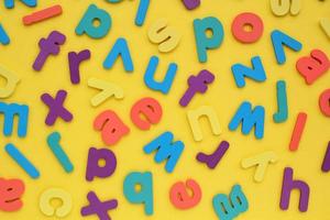 Pile of jumbled messy letters pattern on yellow background. Latin alphabet block colored letters. Dyslexia awareness confusion brain thinking psychology problem. English learning concept. Close up photo