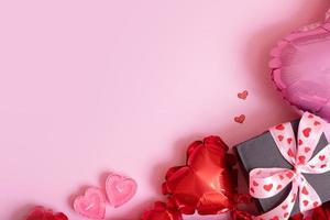 Valentines Day romantic background with copy space. Gift box, candles and red heart shape balloons on pink background photo