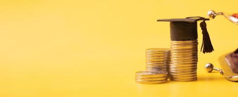 Banner with graduated cap with coins ant wallet on yellow background. Savings for education concept photo