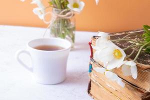 primer plano de flores de anémonas y libros de vinage con taza de bebida. composición de bodegones de primavera, día de la madre o 8 de marzo. foto