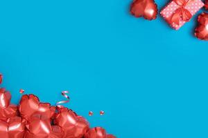 Valentines Day background with copy space. Red heart shape balloons and gift box on turquoise background photo