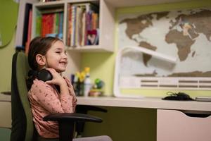 Young girl wearing headphones, enjoys her remote education. Distant studying, homeschooling. photo