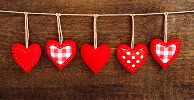 Vintage red hearts hanging on garland on wooden background. Valentines day concept photo