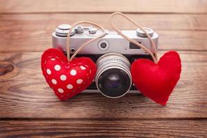 Retro Camera with red hearts on wooden background. photo