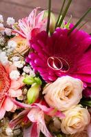 Wedding rings and many colorful flowers with roses bouquet photo