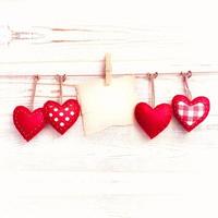 Blank sheet, a note, a torn sheet of paper and vintage red hearts hanging on garland. Valentines day concept photo